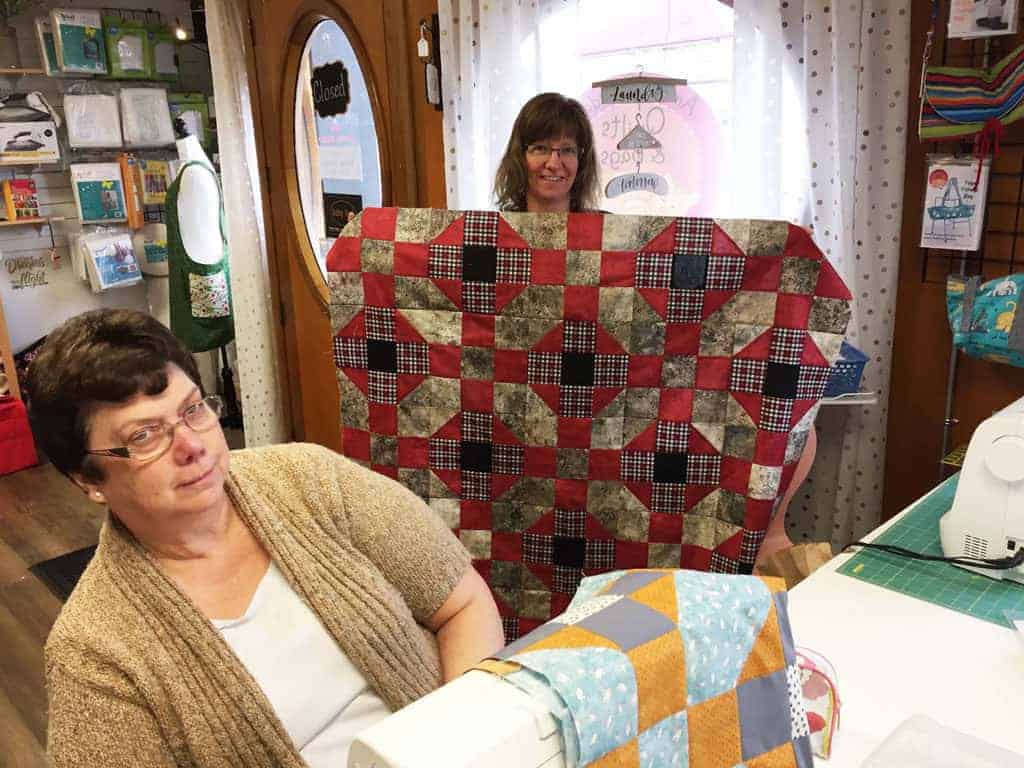 Karen Rombouts holds up her quilt with classmate Nori Quinn.