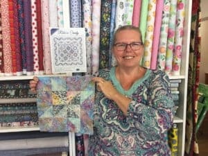 Kelley holding a finished quilt block.