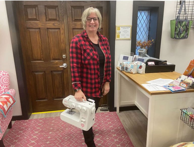 Brenda Miller carrying portable sewing machine.