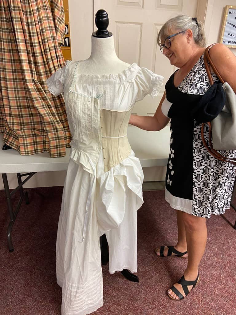 An attendee of a lecture about Fashion History examines undergarments of the time.